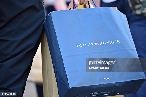 person walking on sidewalk with tommy hilfiger shopping bag - tommy hilfiger designer label stock pictures, royalty-free photos & images