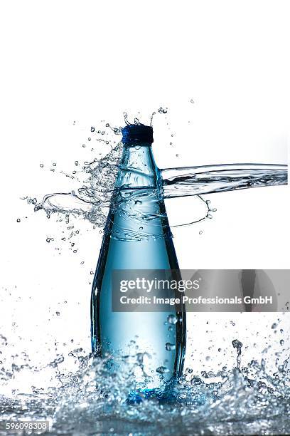 a bottle of water being hit by a jet of water - water bottle splash stock pictures, royalty-free photos & images