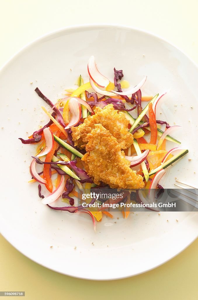 A raw salad with breaded chicken