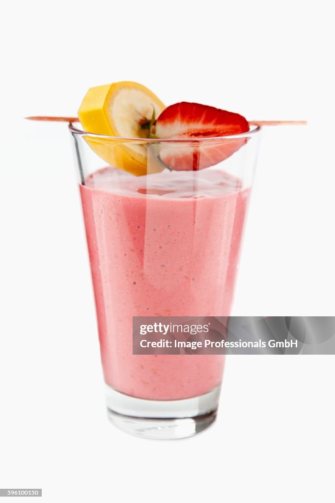 A strawberry smoothie with banana and strawberry pieces on a cocktail stick