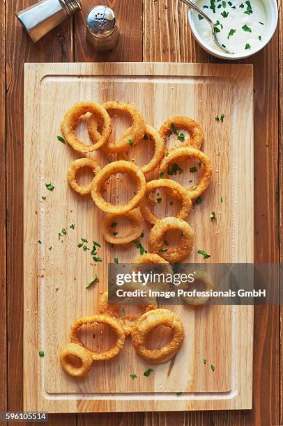 oven baked onion rings sprinkled with parsley and salt on a cutting board; bowl of blue cheese dressing - blue cheese dressing stock pictures, royalty-free photos & images