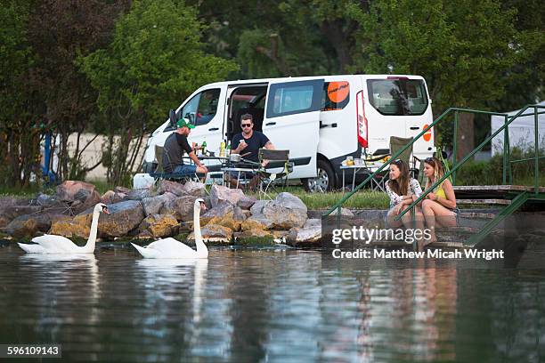 a group prepares dinner lakeside. - freshwater bird - fotografias e filmes do acervo