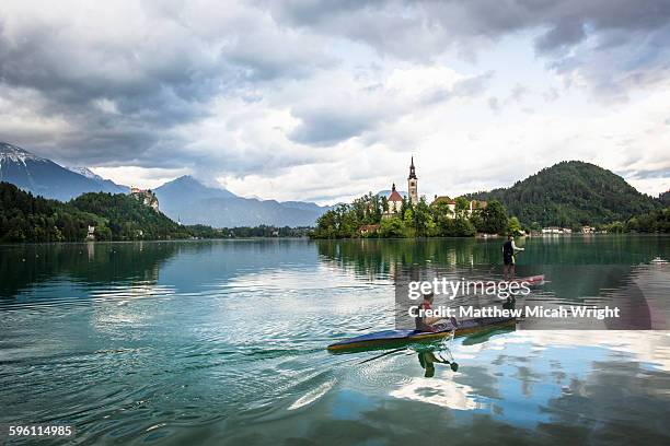 paddling to the iconic church on the lake. - eslovenia fotografías e imágenes de stock