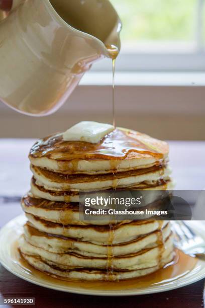 maple syrup being poured over stack of pancakes - maple syrup pancakes fotografías e imágenes de stock