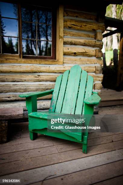 green adirondack chair on porch of log cabin - adirondack chair stockfoto's en -beelden