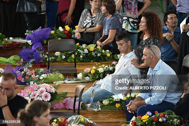 Relatives of earthquake victims mourn next to coffins at a gymnasium arranged in a chapel of rest on August 27 in Ascoli Piceno, three days after a...
