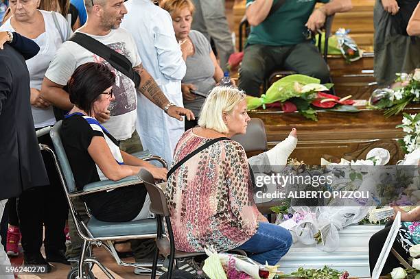 An injured woman mourns next to the coffin of an earthquake victim, in a gymnasium arranged in a chapel of rest on August 27 in Ascoli Piceno, three...
