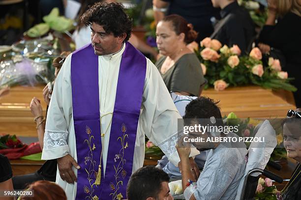 An injured man mourns next to the coffin of an earthquake victim, in a gymnasium arranged in a chapel of rest on August 27 in Ascoli Piceno, three...