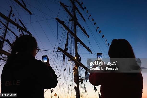 Two women take pictures with their phones of a ships mast during the North Sea Tall Ships Regatta on August 27, 2016 in Blyth, England. The bustling...