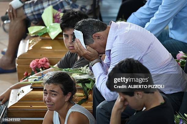 Relatives mourn next to a coffin during a funeral service for victims of the earthquake, at a gymnasium arranged in a chapel of rest on August 27 in...