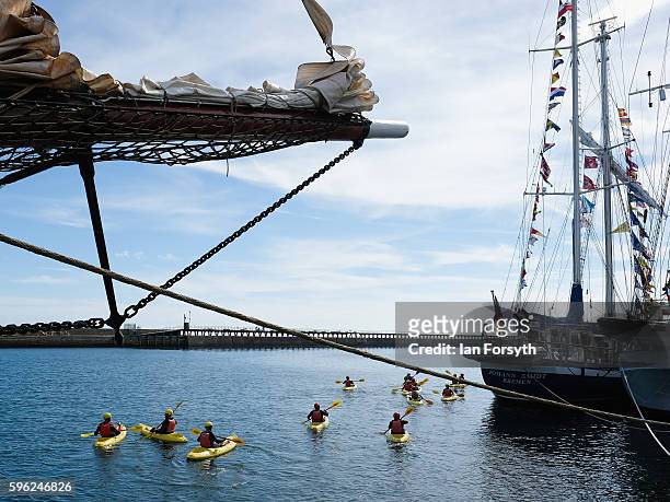 Group of kayakers paddle alongside the ships moored at the quay during the North Sea Tall Ships Regatta on August 27, 2016 in Blyth, England. The...