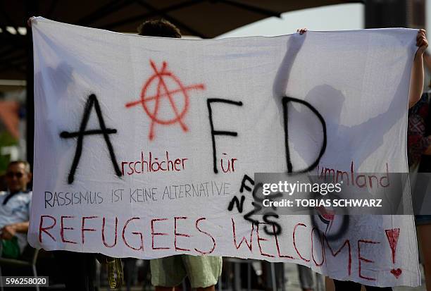 Protesters hold up a banner reading "Arschloecher fuer Dummland" - "Racism is no Alternative" during an election rally of the Alternative for Germany...