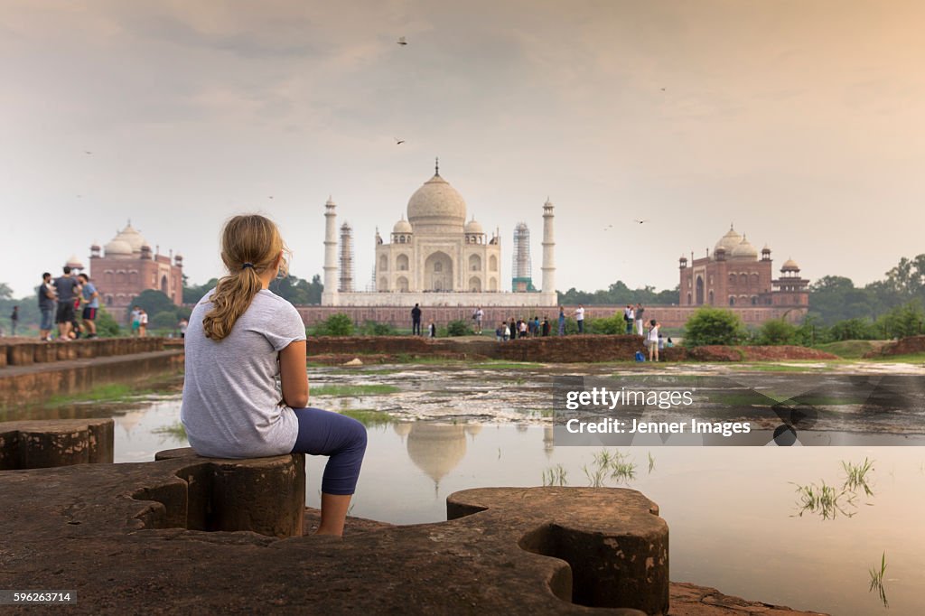 A young girl watching The Taj Mahal at sunset.