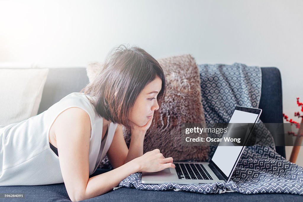 Woman using laptop on sofa