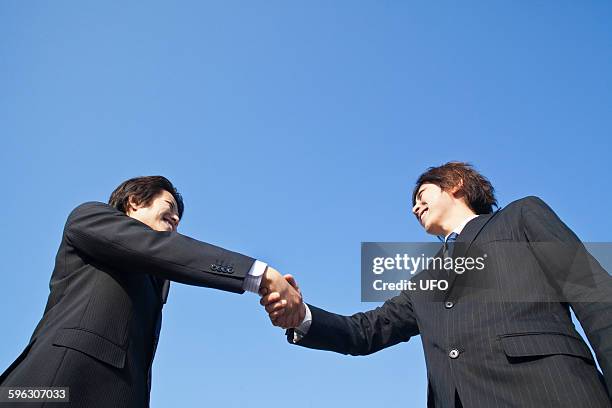 business people shaking hands  - low angle view of two businessmen standing face to face outdoors stock pictures, royalty-free photos & images