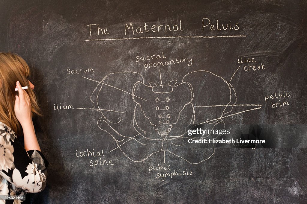 Woman drawing the maternal pelvis with chalk