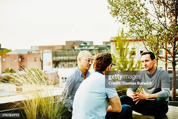 coworkers sitting on office terrace having meeting - asian man sitting casual imagens e fotografias de stock