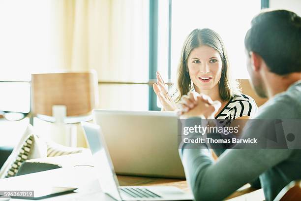 smiling businesswoman in discussion with colleague - sharing two people stock-fotos und bilder