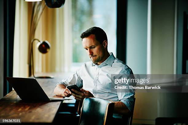 businessman looking at smartphone in office - call us photos et images de collection