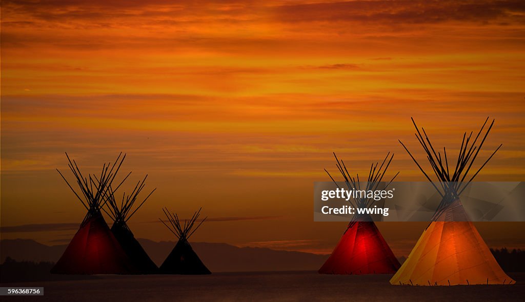 Teepee camp and gold, dark,  sunset- light in teepees