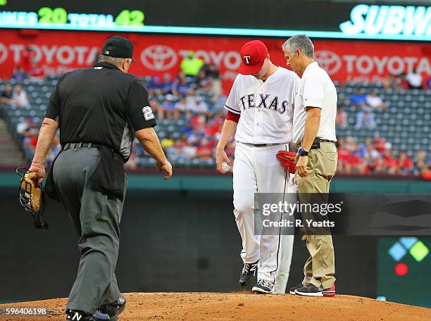 Kevin Harmon trainer for the Texas Rangers talks with Lucas Harrell during in the second inning at Globe Life Park in Arlington on August 16, 2016 in...