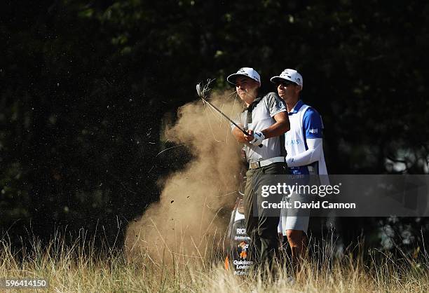 Rickie Fowler plays a shot alongside his caddie Joe Skovron on the 13th hole during the third round of The Barclays in the PGA Tour FedExCup...