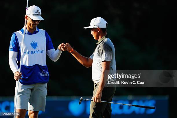 Rickie Fowler celebrates with his caddie Joe Skovron on the 18th green after a three-under par 68 during the third round of The Barclays in the PGA...