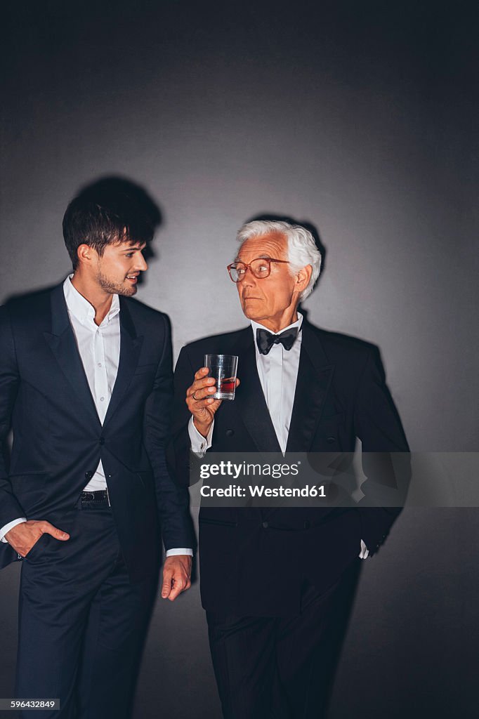 Young man and elegant senior man holding drink
