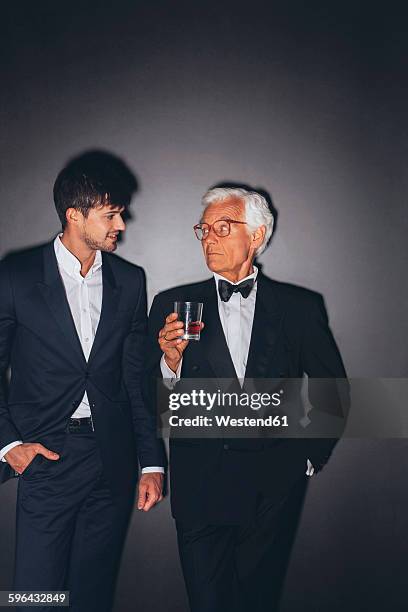 young man and elegant senior man holding drink - tuxedo party stock pictures, royalty-free photos & images