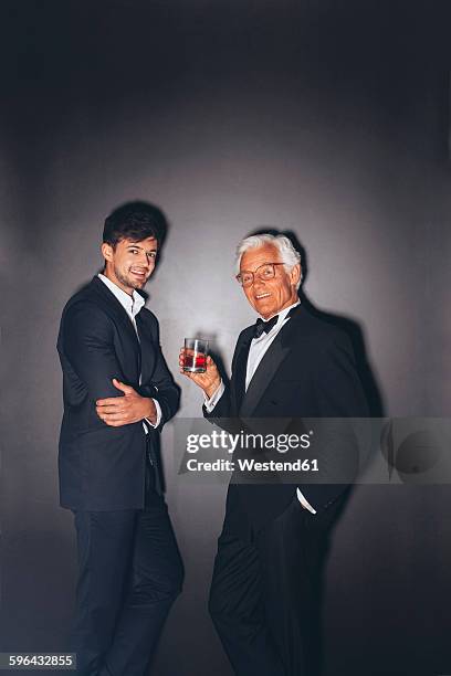 smiling young man and elegant senior man holding drink - smoking fotografías e imágenes de stock