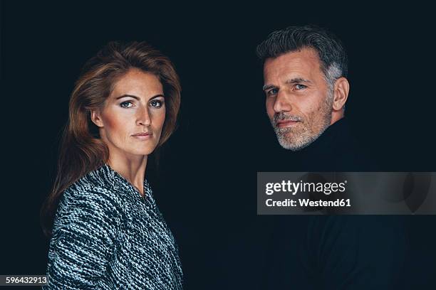 portrait of serious looking couple in front of black background - couple dark background bildbanksfoton och bilder