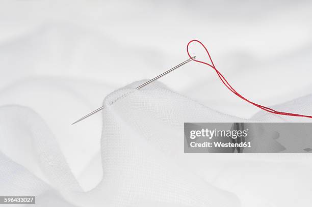red threat in needle eye, white cloth - sewing needle stock pictures, royalty-free photos & images