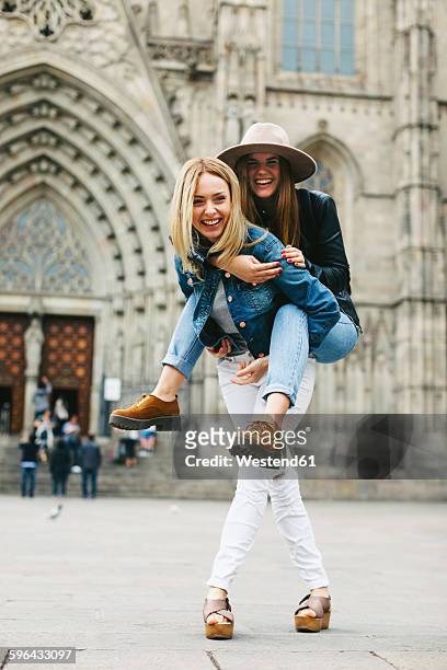 spain, barcelona, happy young woman carrying friend piggyback in the city - おんぶ ストックフォトと画像