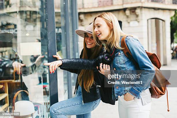 two young women looking in shop window - scoperta foto e immagini stock