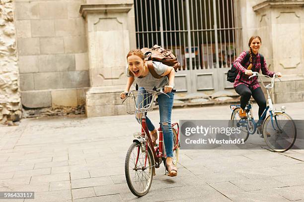 spain, barcelona, two happy young women riding bicycle in the city - barcelona free stockfoto's en -beelden