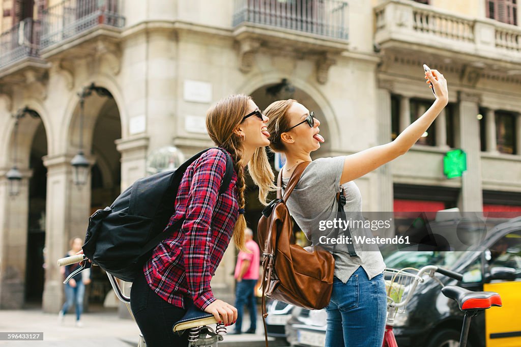 Spain, Barcelona, two playful young women taking a selfie