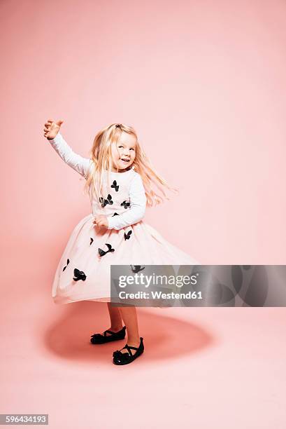 smiling blond little girl dancing in front of pink background - the little white dress stock-fotos und bilder