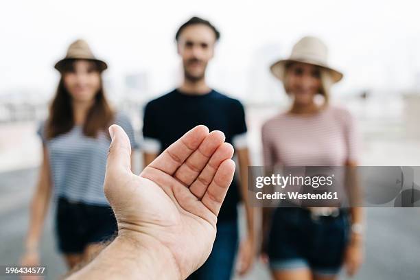 spain, barcelona, gesture of man's hand with three friends standing in the background - inviting gesture stock pictures, royalty-free photos & images