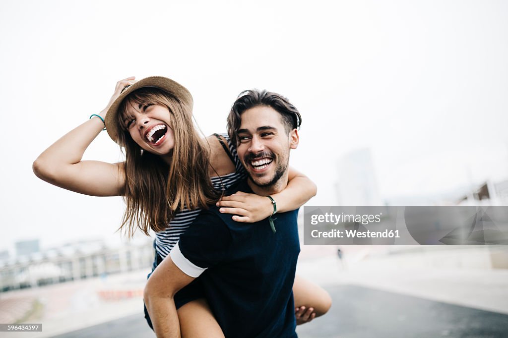 Spain, Barcelona, young man giving his girlfriend a piggyback ride