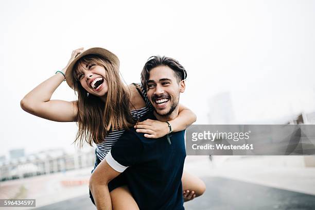 spain, barcelona, young man giving his girlfriend a piggyback ride - coppia eterosessuale foto e immagini stock
