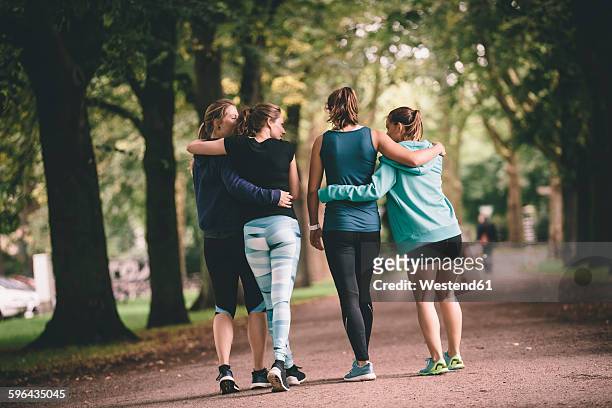 four female joggers in park - athleticism stockfoto's en -beelden