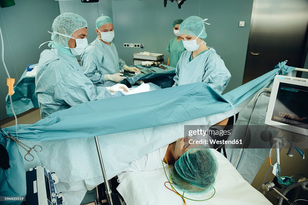 Team operating a woman on surgery table