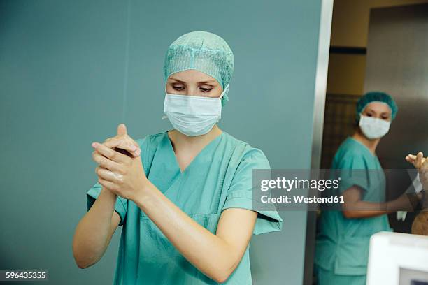 female surgeon disinfecting her hands before surgery - disinfection stock pictures, royalty-free photos & images