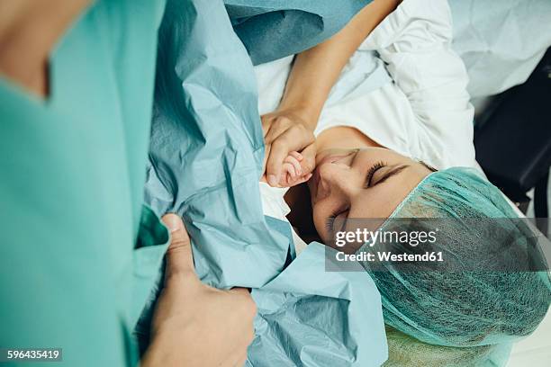 mother touching hand of her newborn right after c-section - kaiserschnitt stock-fotos und bilder