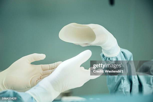 operating room nurse handing silicone implant to surgeon during surgery - silicone foto e immagini stock