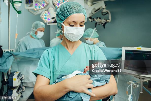 operating room nurse holding newborn in operating room - hospital nursery ストックフォトと画像