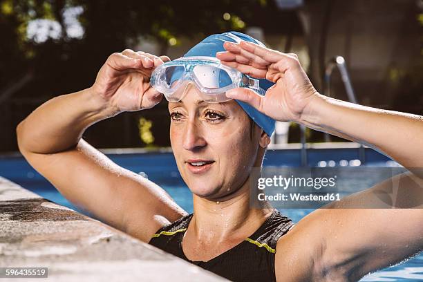 female triathlete in swimming pool lifting goggles - cuffia da nuoto foto e immagini stock