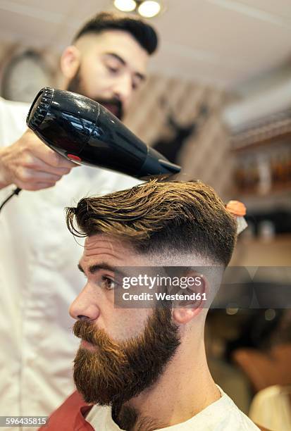 barber blow-drying hair of a customer - half shaved hair stock pictures, royalty-free photos & images