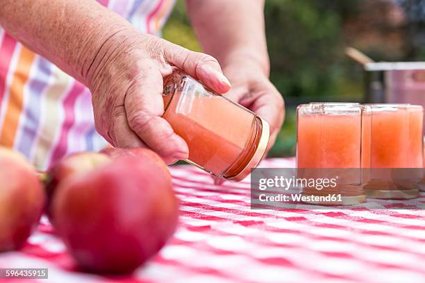 senior woman turning glass of homemade applesauce, close-up - homemade apple sauce stock pictures, royalty-free photos & images