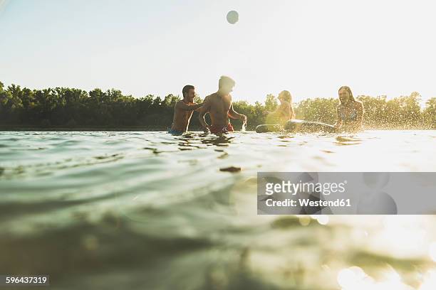 happy friends with inner tubes and ball in water - river bathing imagens e fotografias de stock